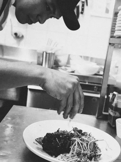 Chef Quan plating a dish at Paper Plate Restaurant